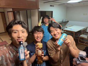 4人のゼミ生が各々お酒の瓶や缶を持っている