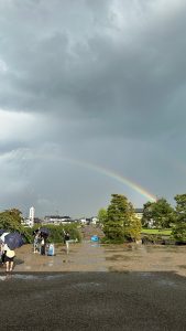 佐藤ゼミ、合宿の様子3。虹がかかった空の下にゼミ生たちが各々写真をとったりしている。