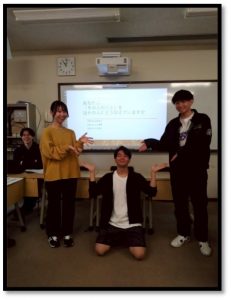 大学の教室でゼミの発表を行っている様子。プロジェクターのスクリーンを背景に、3人の学生がユーモラスなポーズを取っている。スクリーンには**「あなたは、「その人のこと」をほかの人にどう伝えていますか」**という発表資料のタイトルが表示されている