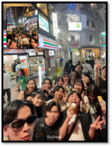 夜の繁華街の路上で撮られたBeRealの写真。多くのゼミ生が笑顔で集まり、数名がピースサインをしている。手前にいる男性はアイスクリームを食べている。左上の小窓も同じような状況。