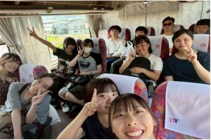 バスの車内での集合写真。ゼミの学生たちが笑顔でカメラに向かってポーズを取り、旅の楽しそうな雰囲気。