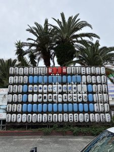 白、青、赤の提灯が格子状に並べられた歓迎看板。提灯には旅館名や名産品と共に、「花と海といで湯のまち 伊東温泉へようこそ」というメッセージが書かれている。上部にはヤシの木が生い茂り、南国のような雰囲気。